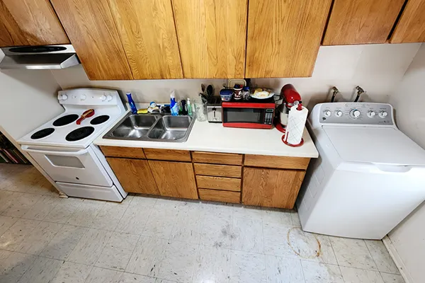 The same kitchen as the previous image is shown after being cleared and cleaned by Heritage Home Revival. The surfaces have all been cleaned, the trash has been removed, and it is orderly and liveable.